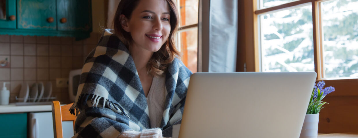 smiling student working on laptop in kitchen 