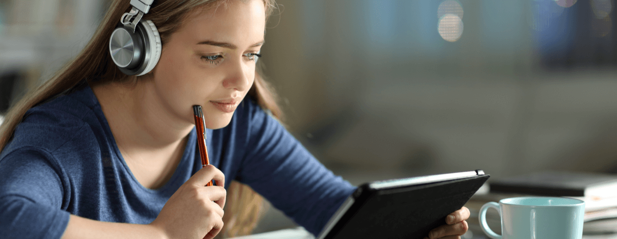 Teenage student, teen girl, taking an online class on tablet at home, wearing headphones for online learning Teenage student, teen girl, taking an online class on tablet at home, wearing headphones for online learning
