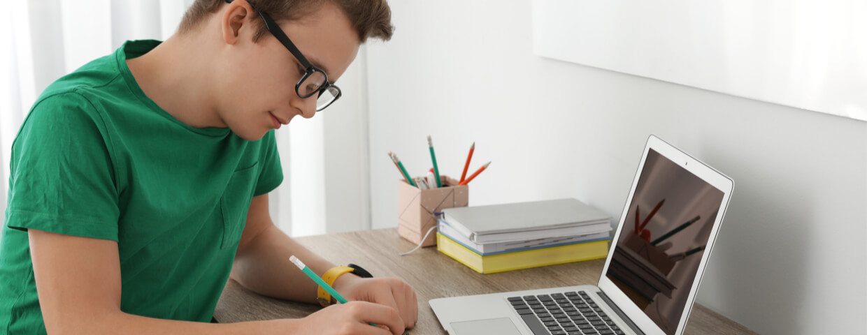 Teenager boy working on schoolwork, online school
