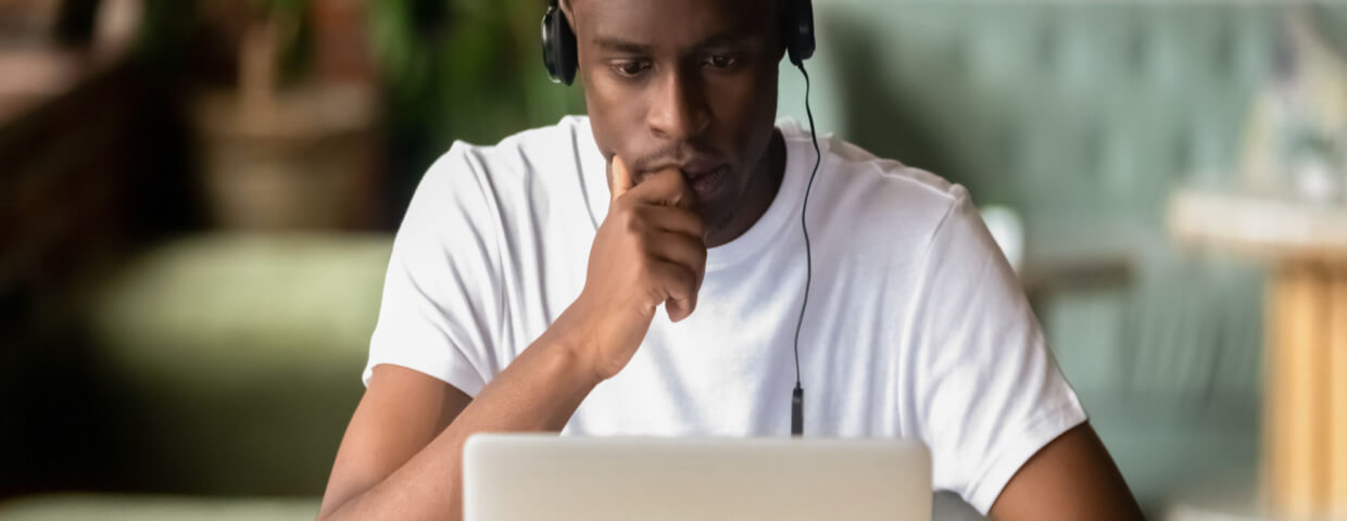 male high school student taking class online with laptop & headphones