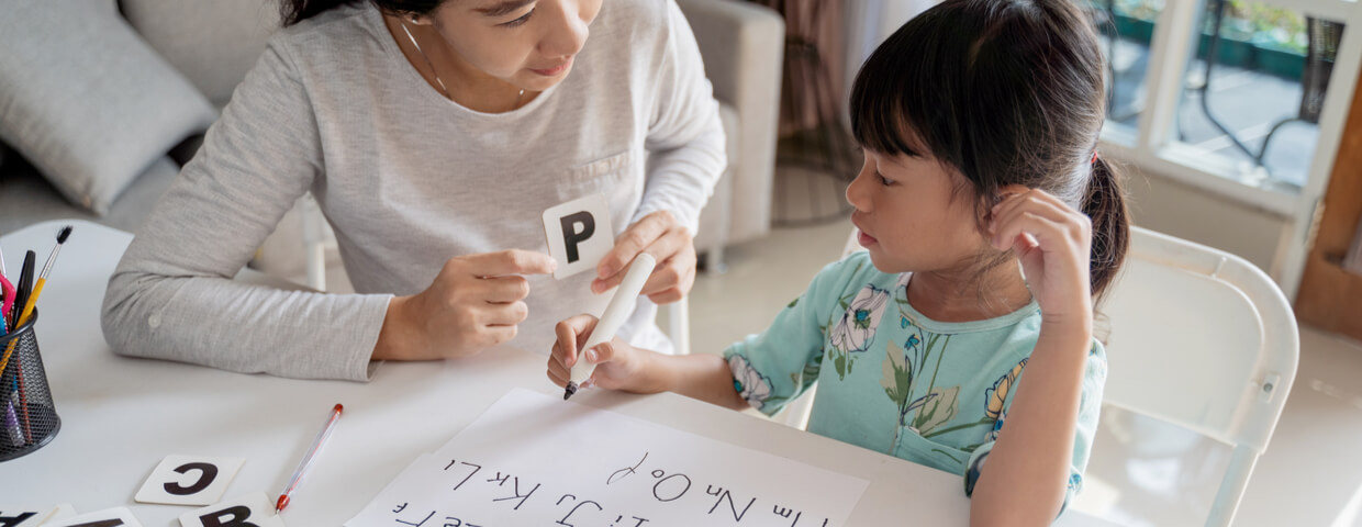 mother and daughter learning to read and write letter at home together. homeschooling activity