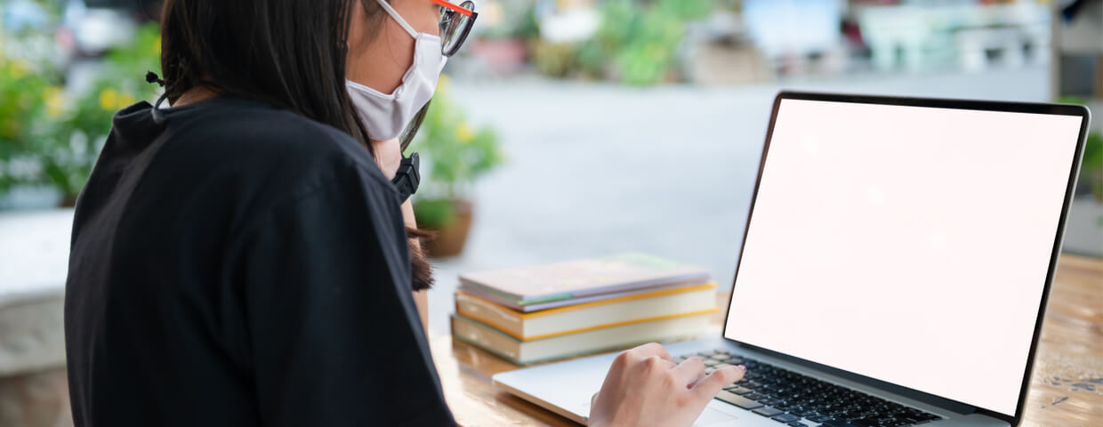 student in face mask at laptop