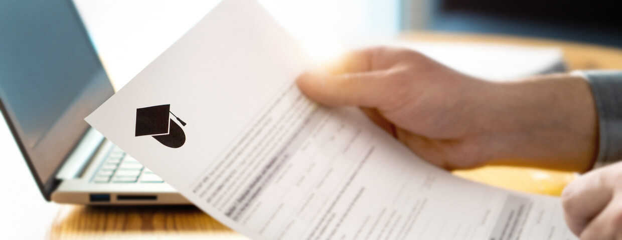 High school student filling out a college or university application, laptop in background