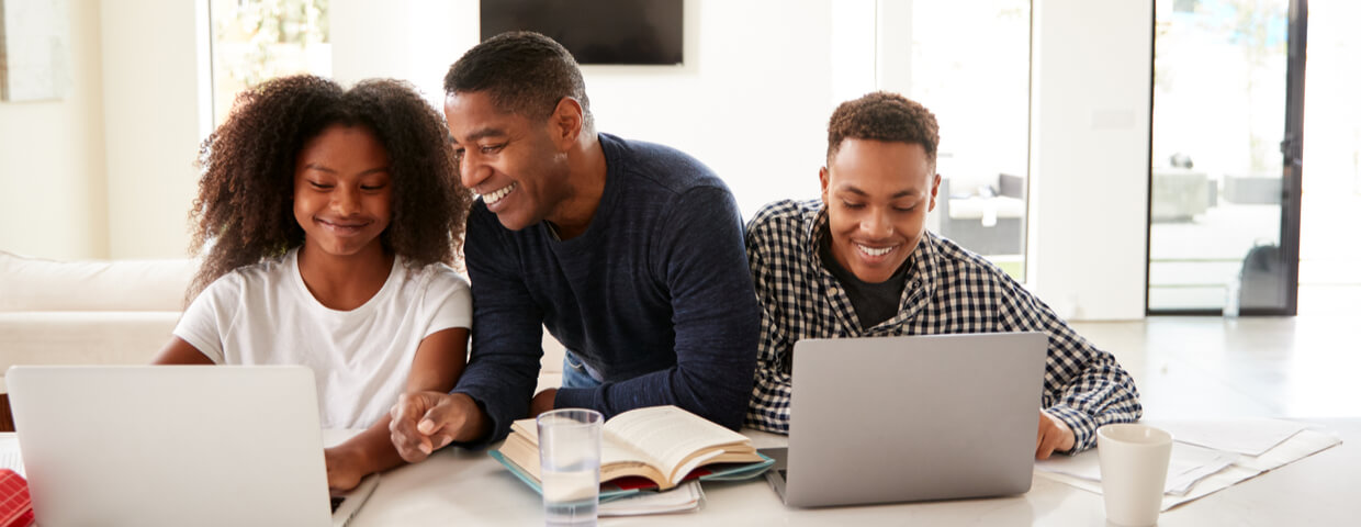 Smiling dad helping his teen kids with their homework, front view, close up
